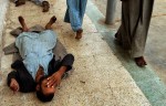 A patient lies on the floor at Rashad psychiatric hospital as other patients file past. Many of the men are extremely mentally ill and a in nearly catatonic state.