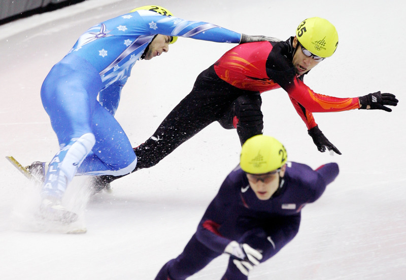 Alex Izykowski, of the USA, pulls away as Yuri Confortola, upper left, of Italy, and Takahiro Fujimoto, of Japan, upper right, collide in the men's 5000 meter relay semifinal in short-track speed skating at the 2006 Winter Olympics.