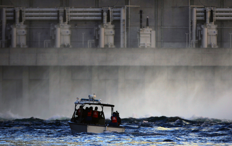 A small boat goes up to the base of the Glen Canyon Dam during a water release on the Colorado River. The water release mimics the seasonal flow of the river and helps redeposit sediment. (Photo by Chris Schneider)