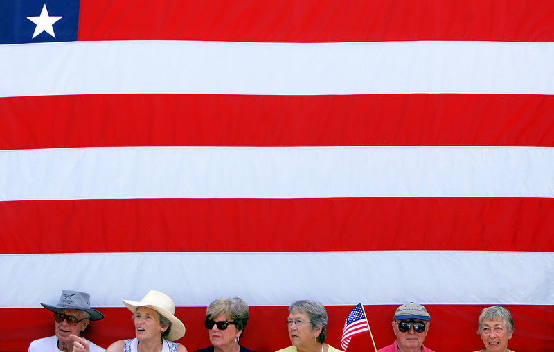 Clinton supporters sit beneath a flag as they wait at a Hillary Clinton campaign event with her husband former President Bill Clinton at the University of Iowa in Iowa City, Iowa, on Tuesday, July 3, 2007. (Photo by Chris Schneider)